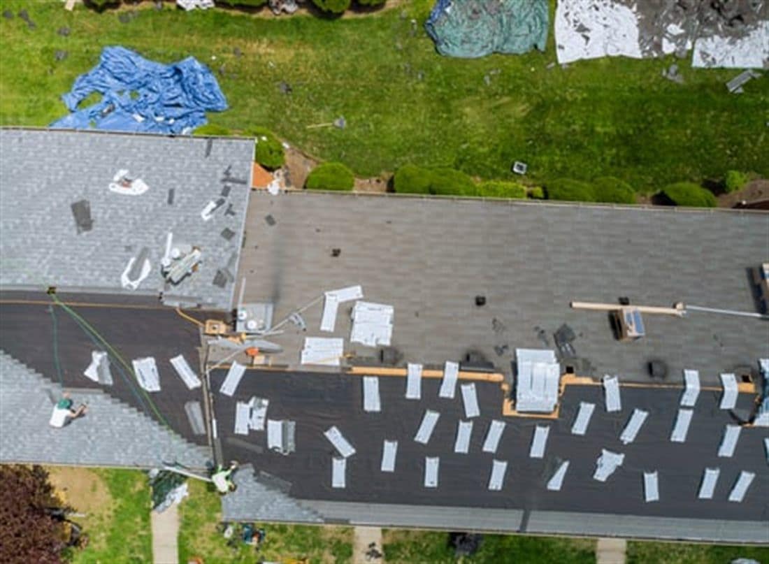 Aerial view of a residential roof being torn off and replaced before the rainy season
