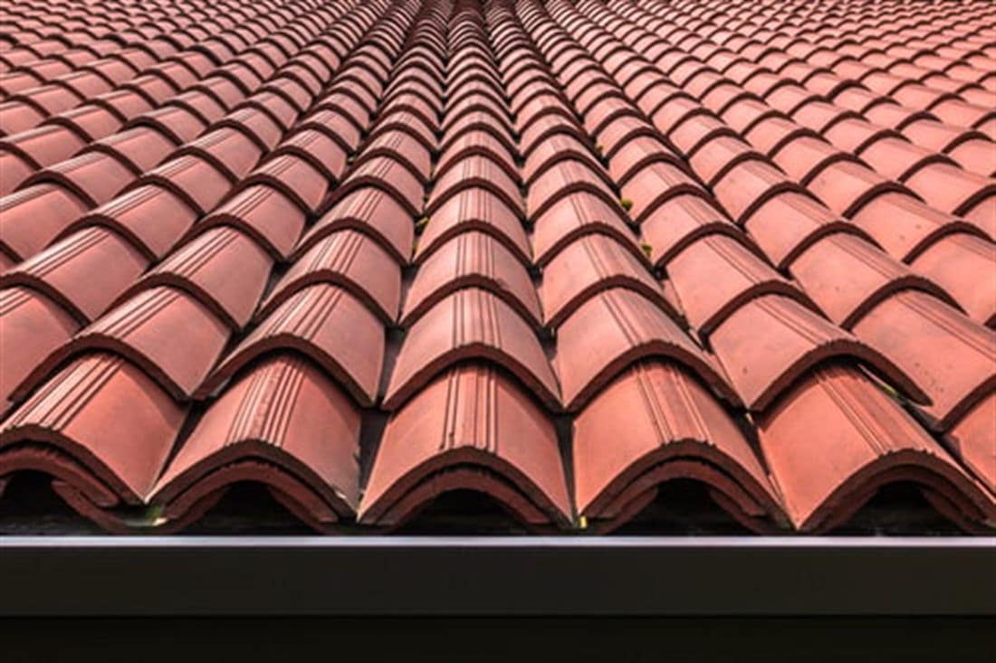 Red clay tile roof on a Southern California home under clear blue sky
