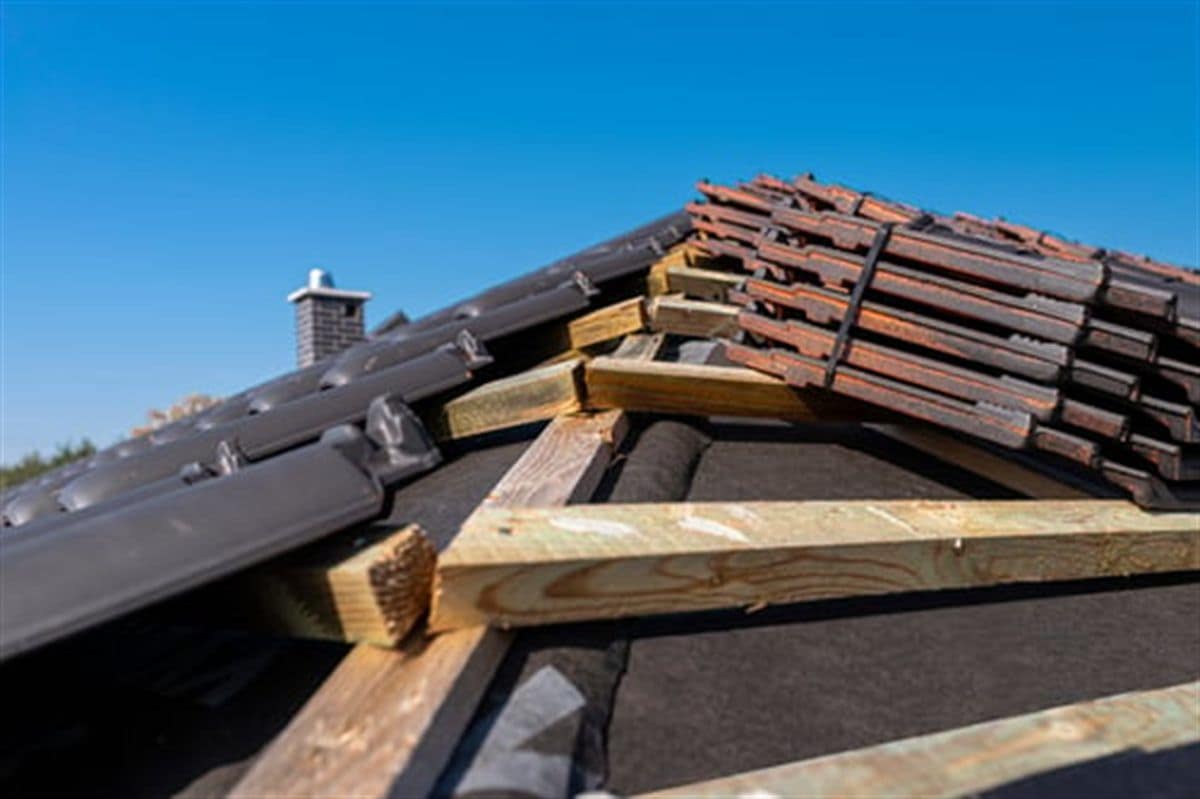 Roofer repairing cracked tiles and flashing on a residential roof in Riverside County